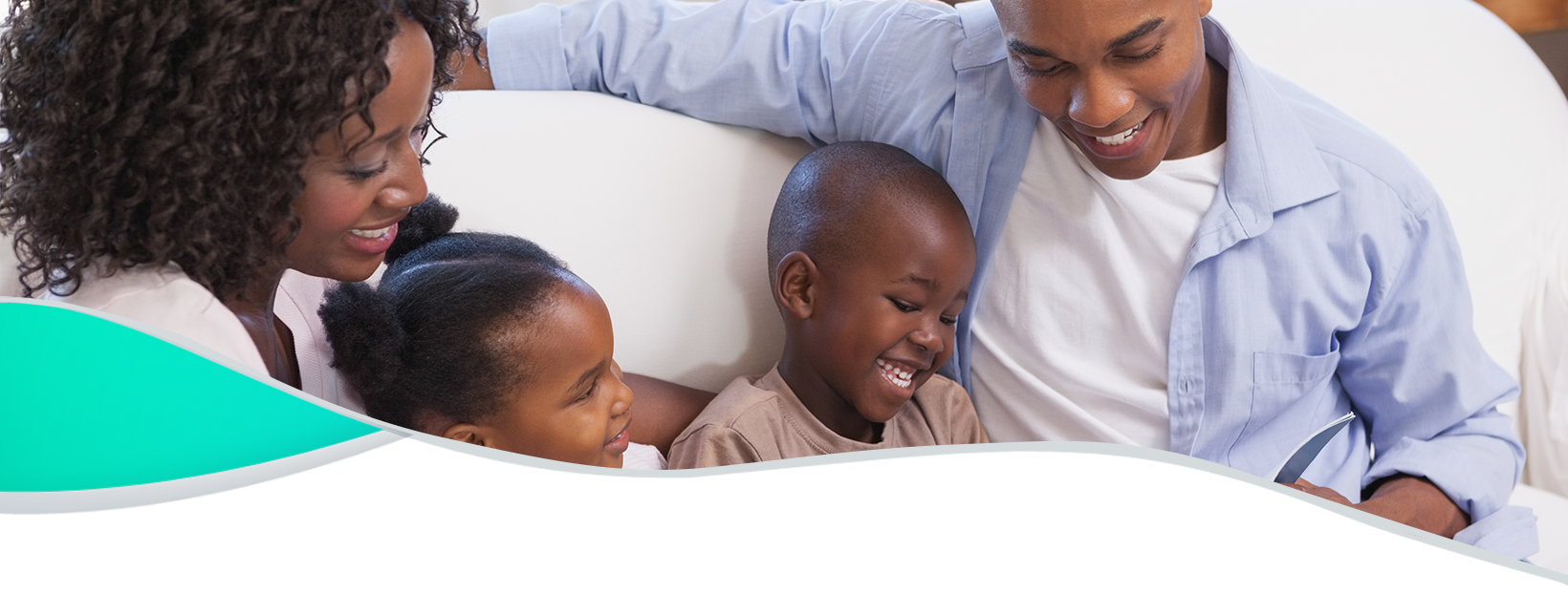 Happy family sitting on couch together reading book.