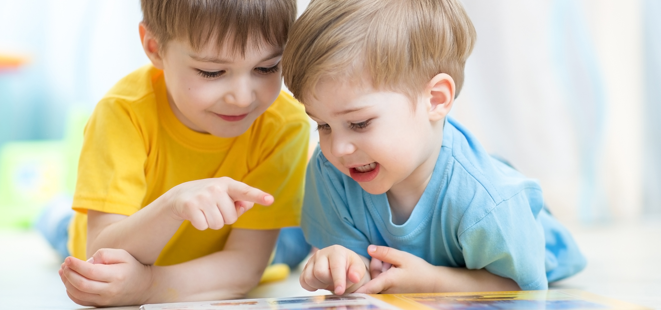 Two toddler boys looking at a book.