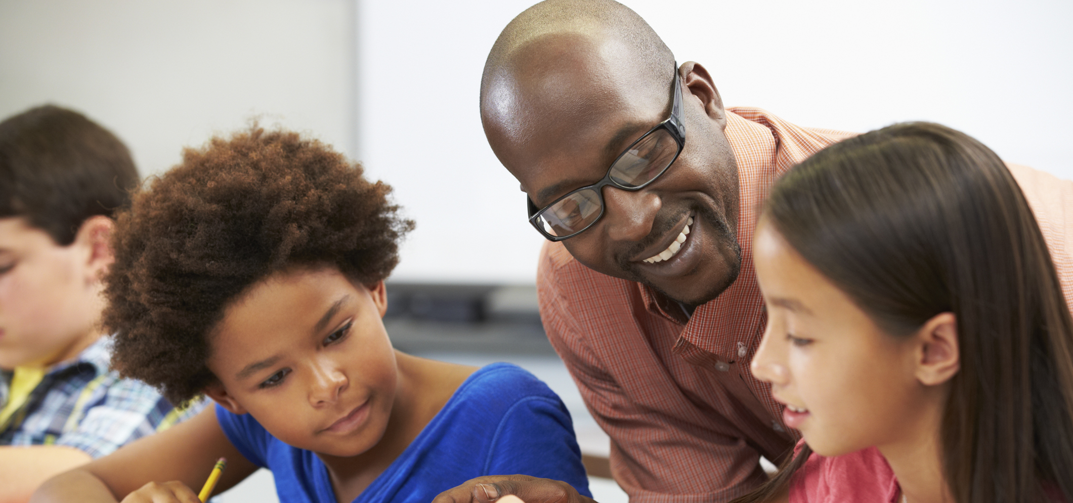 A male teacher educating two elementary grade school students.